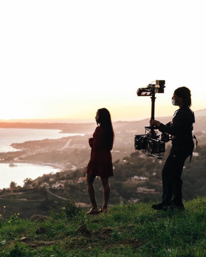 Anthony silhouetted with a Steadicam rig against a sunset over the coast