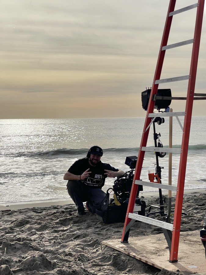 Anthony shooting low on a beach at dusk with a ladder rig behind