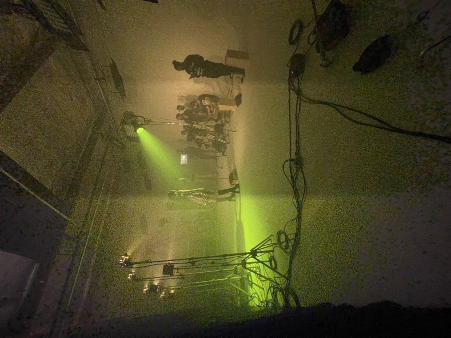 A green-lit studio set with crew and a camera rig
